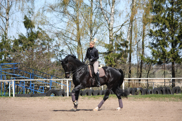 Mujer rubia montando caballo negro
 - Foto, imagen