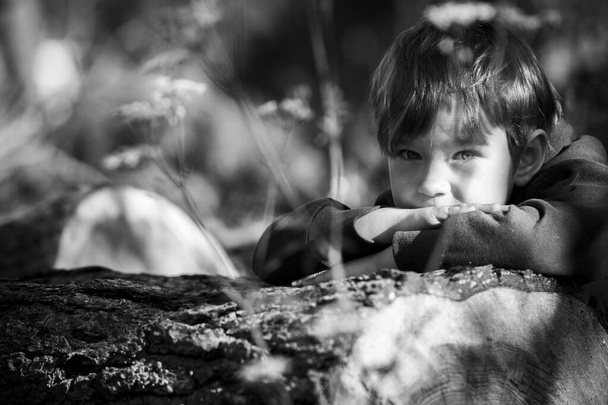 Ένα μικρό αγόρι στο χωριό, από κοντά. Ασπρόμαυρη φωτογραφία. - Φωτογραφία, εικόνα