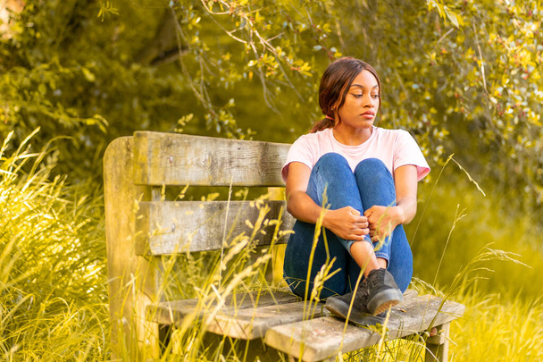 夏の午後公園のベンチに座っている若い黒人女性は - 写真・画像