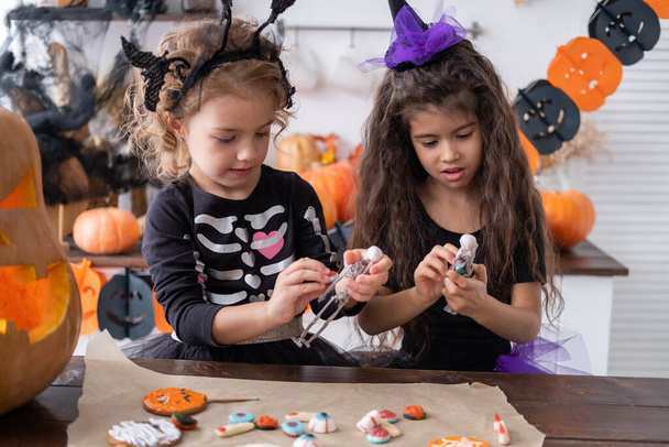 deux enfants diversifiés fille en costume de sorcière, s'amuser à la maison dans la cuisine, célébrer Halloween. - Photo, image