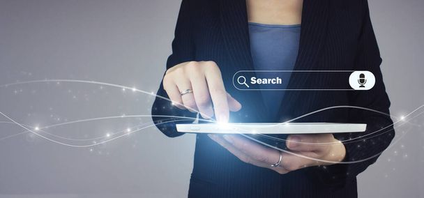 データ検索技術検索エンジン最適化。ビジネス女性の手の中に白いタブレットデジタルホログラム検索アドレスとグレーの背景にナビゲーションバーのアイコンサイン - 写真・画像