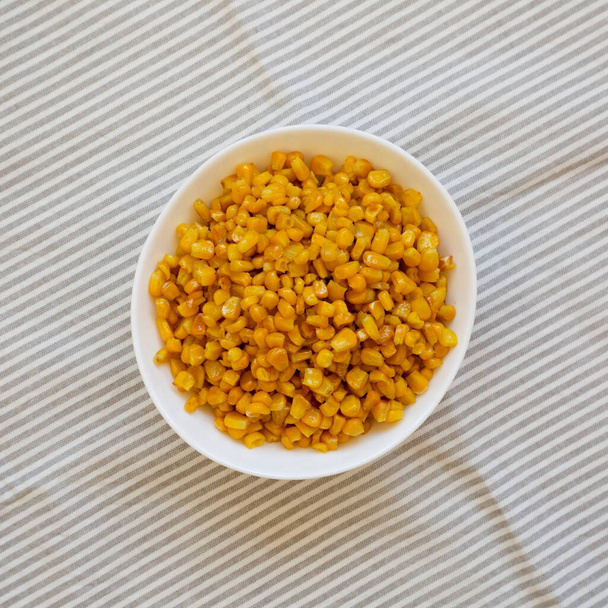 Maïs doux rôti jaune dans un bol blanc, vue de dessus. Couché plat, au-dessus, d'en haut.  - Photo, image