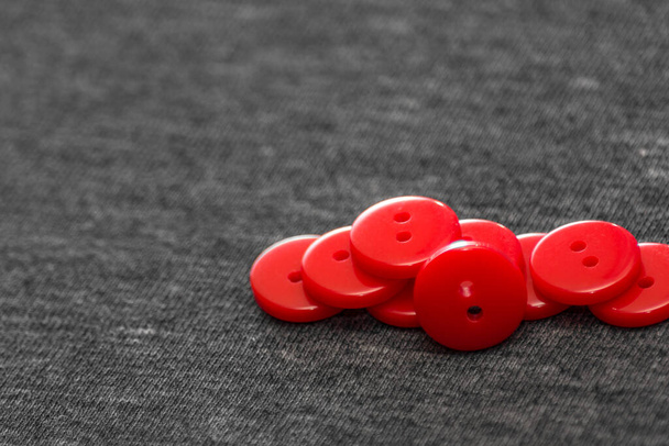 Bright red buttons. Gray fabric. Blurred background. The concept of the clothing industry and decor. - Photo, Image