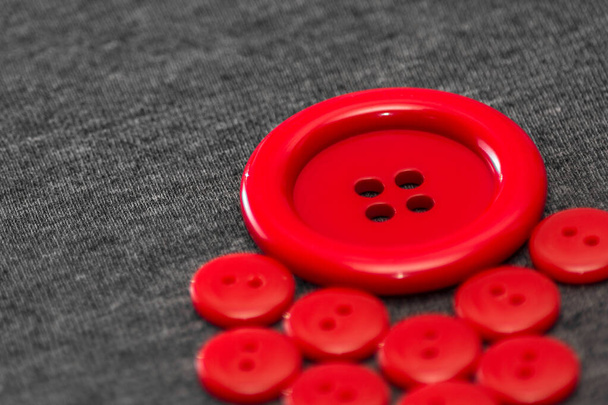 Bright red buttons. Gray fabric. Blurred background. The concept of the clothing industry and decor. - Foto, afbeelding