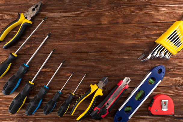 Work tool of the wizard. Screwdrivers, pliers, wire cutters, building level, tape measure, hammer, wrenches, square and other tools on a wooden surface. Free space for text. - Foto, imagen