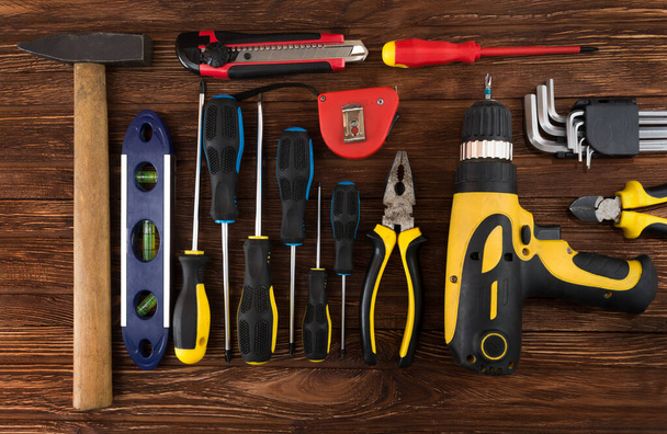 Work tool of the wizard. Screwdrivers, pliers, wire cutters, building level, tape measure, hammer, wrenches, square and other tools on a wooden surface. Free space for text. - 写真・画像