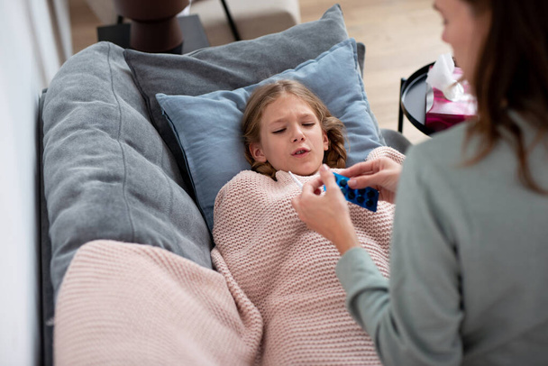 Mother gives bitter pills to daughter who has a cold - Foto, Bild