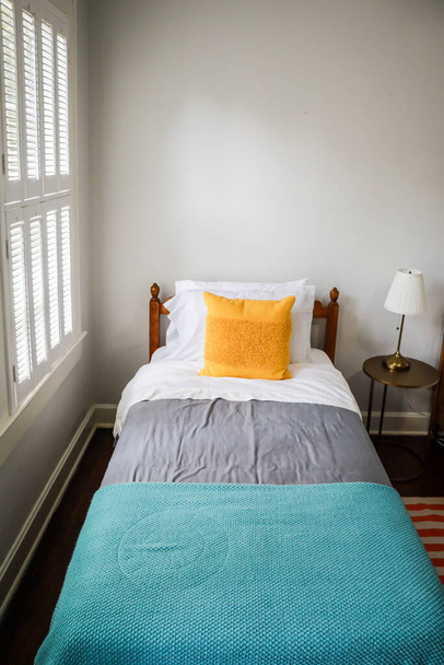 トルコ石とグレーのベッドスプレッドと黄色の装飾枕を備えたシングルツインベッドルーム - 写真・画像