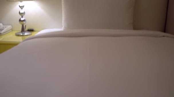 Un letto matrimoniale con lenzuola bianche in una camera d'albergo. Interno bianco camera da letto minimalista. Elegante interno di camera contemporanea con letto comodo, Home nordico - Filmati, video
