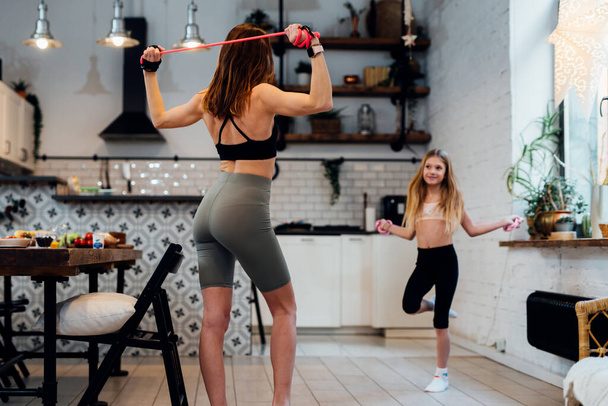 Joven madre haciendo ejercicio en casa con su hija. - Foto, Imagen