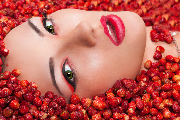 Beautiful female face in wild strawberry - Фото, изображение