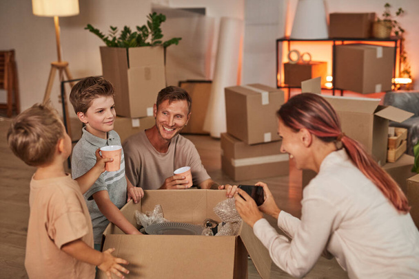 Большая семья распаковывает коробки в новом доме - Фото, изображение