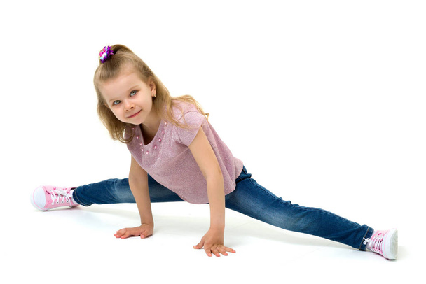 Adorable girl in casual outfit doing split on floor - Zdjęcie, obraz