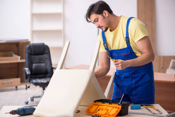 Young male carpenter repairing chair in the office - Valokuva, kuva