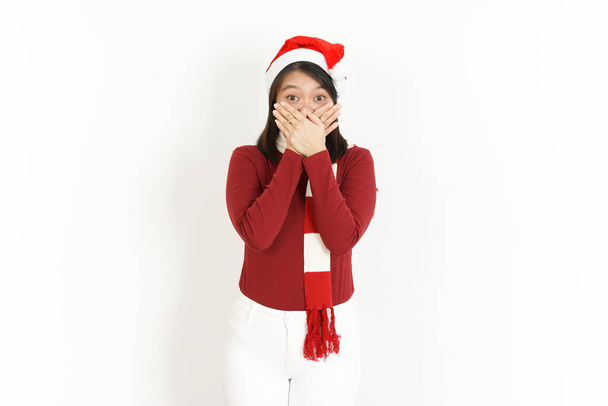 Cubrir la boca con la mano de hermosa mujer asiática con cuello alto rojo y sombrero de Santa aislado sobre fondo blanco - Foto, imagen