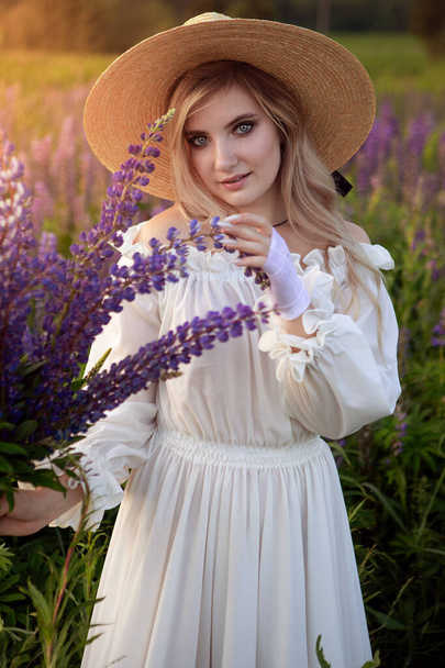A retro lady enjoys the beauty of a blooming lupine field. The concept of harmony. - Φωτογραφία, εικόνα