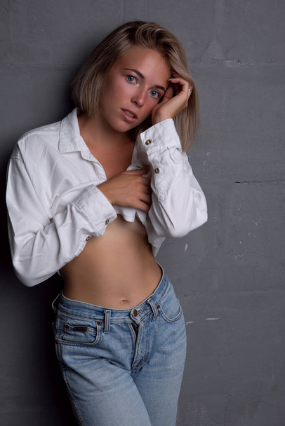 Sexy young woman with a beautiful figure in jeans and an unbuttoned shirt - Foto, Imagen
