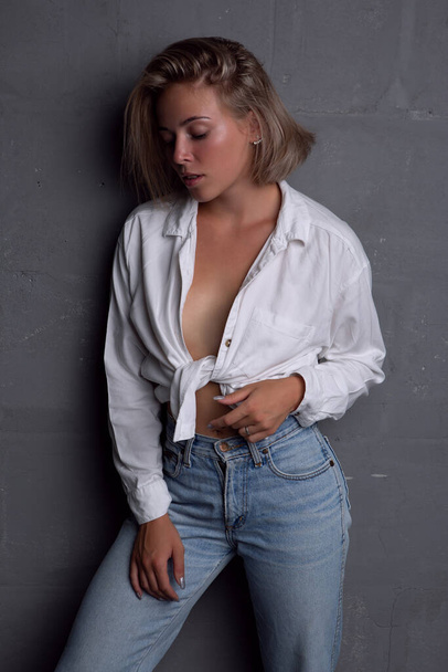 Sexy young woman with a beautiful figure in jeans and an unbuttoned shirt - Foto, Imagem