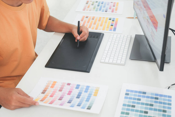 Graphic designer working with color samples for selection. Graphic designer at work. Color swatch samples. Young photographer and graphic designer at work in office. - Photo, Image