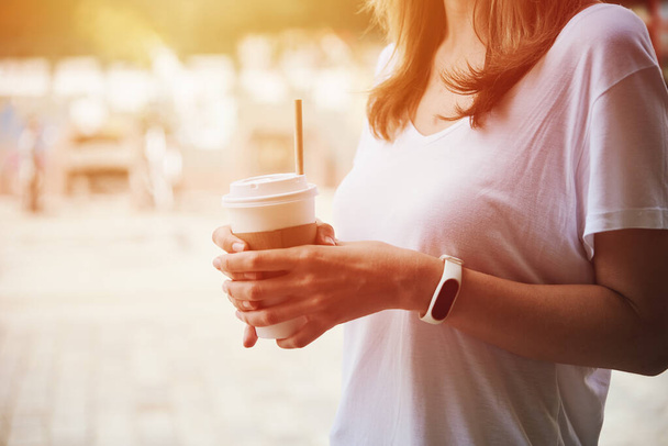 Woman holds paper coffee cup at city street - Photo, Image