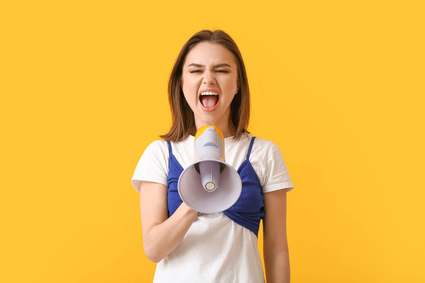 Protesting young woman with megaphone on color background - Foto, Bild