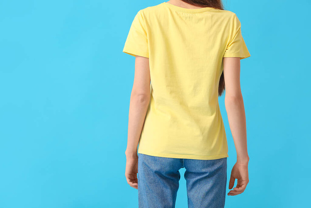 Jeune femme en t-shirt moderne sur fond couleur, vue arrière - Photo, image