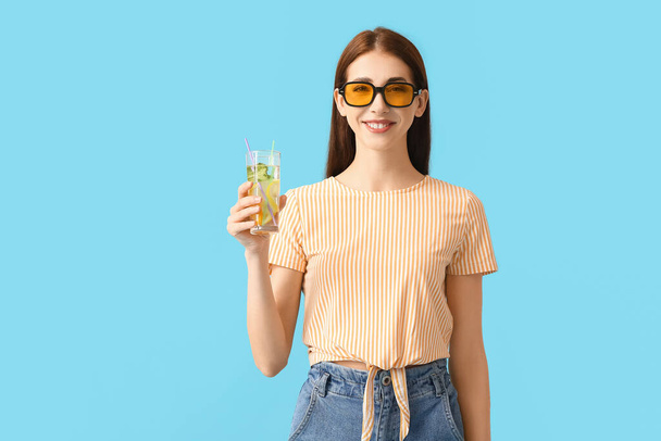 Hermosa joven con limonada fresca sobre fondo de color - Foto, Imagen