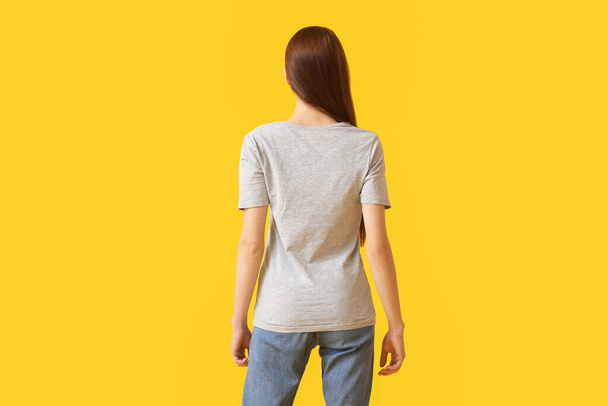 Young woman in modern t-shirt on color background, back view - Photo, Image