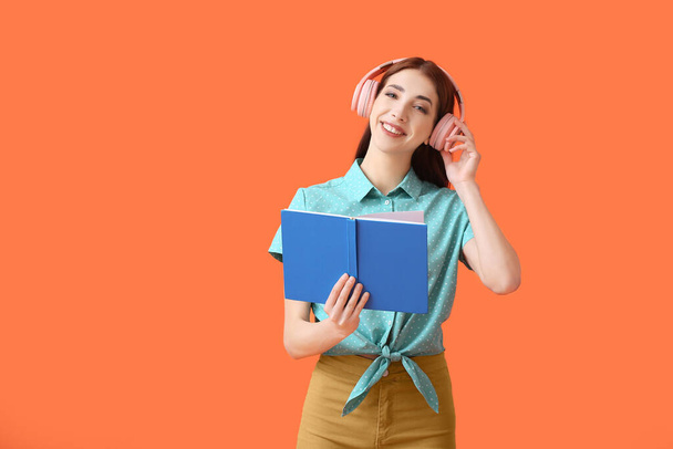 Jeune femme avec écouteurs et livre sur fond de couleur - Photo, image