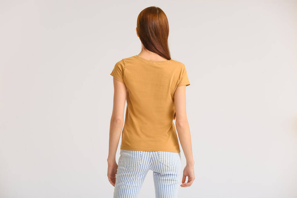 Junge Frau in modernem T-Shirt auf hellem Hintergrund, Rückseite - Foto, Bild