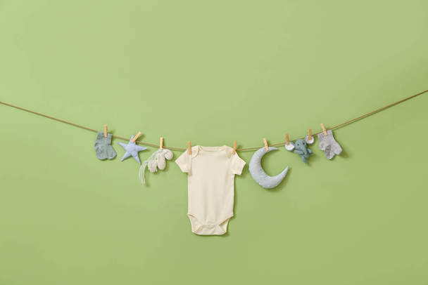Stílusos baba ruhák és játékok lóg kötélen ellen zöld háttér - Fotó, kép