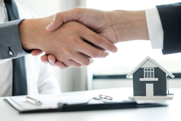 ビジネスマンやブローカーの不動産仲介業者は、住宅保険を購入し契約に署名するための交渉を完了した後、握手をします。住宅保険の概念. - 写真・画像