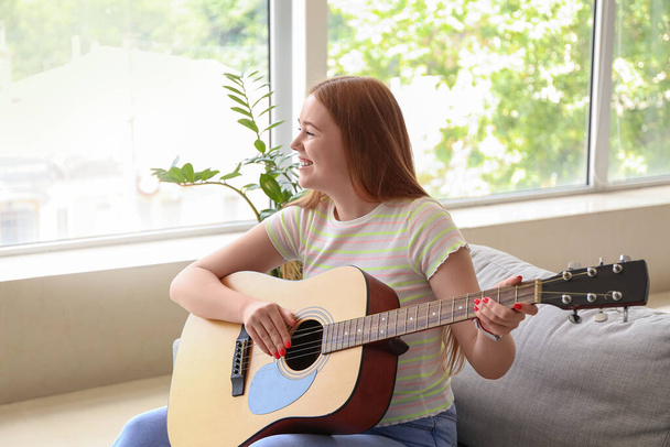 Молода жінка грає на гітарі вдома
 - Фото, зображення
