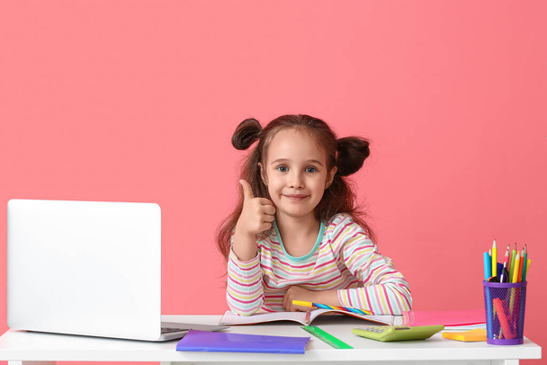 Μικρό κορίτσι δείχνει αντίχειρα-up στο τραπέζι στο φόντο χρώμα - Φωτογραφία, εικόνα