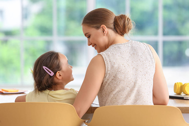 Petite fille avec sa mère faisant des leçons à la maison - Photo, image