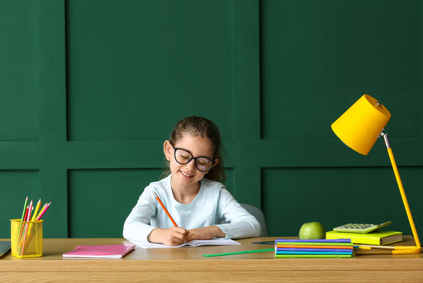 色の背景でテーブルで宿題をしている女の子 - 写真・画像