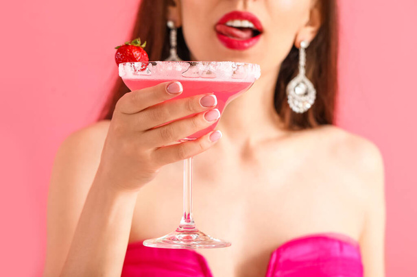 Beautiful young woman with cocktail on color background - 写真・画像