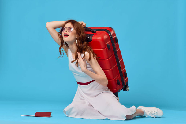 mujer alegre con maleta roja sentado en el suelo emociones aisladas fondo - Foto, imagen