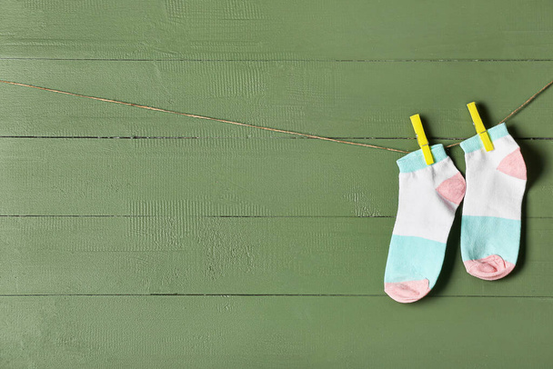 Ζεύγος κάλτσες κρεμασμένες σε σχοινί σε πράσινο ξύλινο φόντο - Φωτογραφία, εικόνα