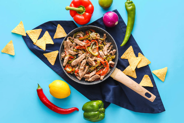 Smažená pánev s chutným hovězím Fajita, nachos a zelenina na barevném pozadí - Fotografie, Obrázek