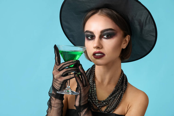 Mooie jonge vrouw in Halloween kostuum van heks op kleur achtergrond - Foto, afbeelding