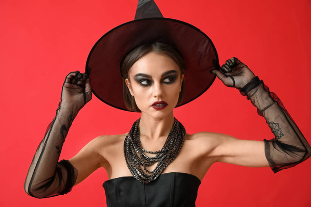 Beautiful young woman in Halloween costume of witch on color background - Foto, Imagem