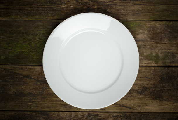 Empty white plate on wooden table - 写真・画像