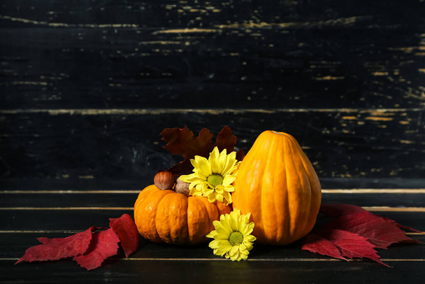 Autumn composition with pumpkins and flowers on dark wooden background - 写真・画像