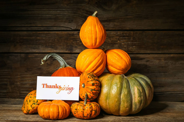 Different pumpkins and text THANKSGIVING on wooden background - Photo, Image