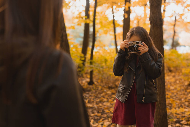 Enfant prenant en photo sa mère sur caméra rétro dans le parc d'automne. Loisirs et concept de loisirs. - Photo, image