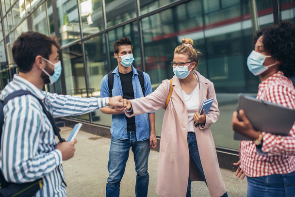 Univerzitní studenti stojící a zdravící s pěstí venku, coronavirus a zpět na normální koncepci. - Fotografie, Obrázek