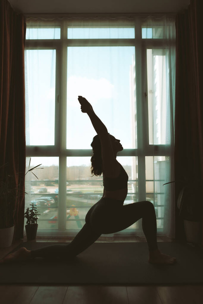 жінка робить йогу вдома біля великого вікна здоровий спосіб життя
 - Фото, зображення