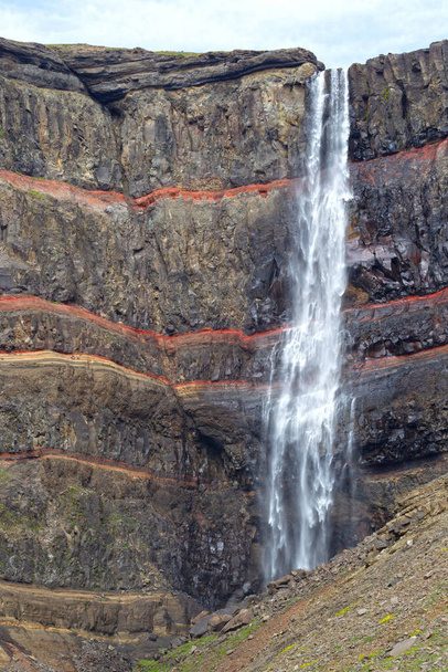 Hengifoss es la segunda cascada más alta de Islandia. Se encuentra en el este de la isla - Tal vez lo más especial de la cascada son las capas multicolores en la roca de basalto detrás de la cascada - Foto, Imagen