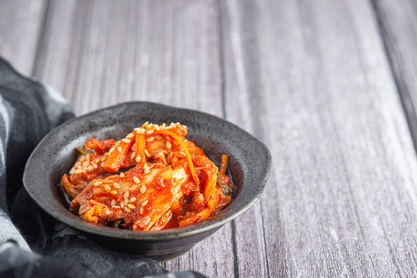 Κάτοψη των παραδοσιακών κορεάτικων πιάτων (Kimchi) σε ένα μπολ σε ξύλινο τραπέζι. Χώρος για κείμενο. Έννοια των κορεατικών τροφίμων. - Φωτογραφία, εικόνα